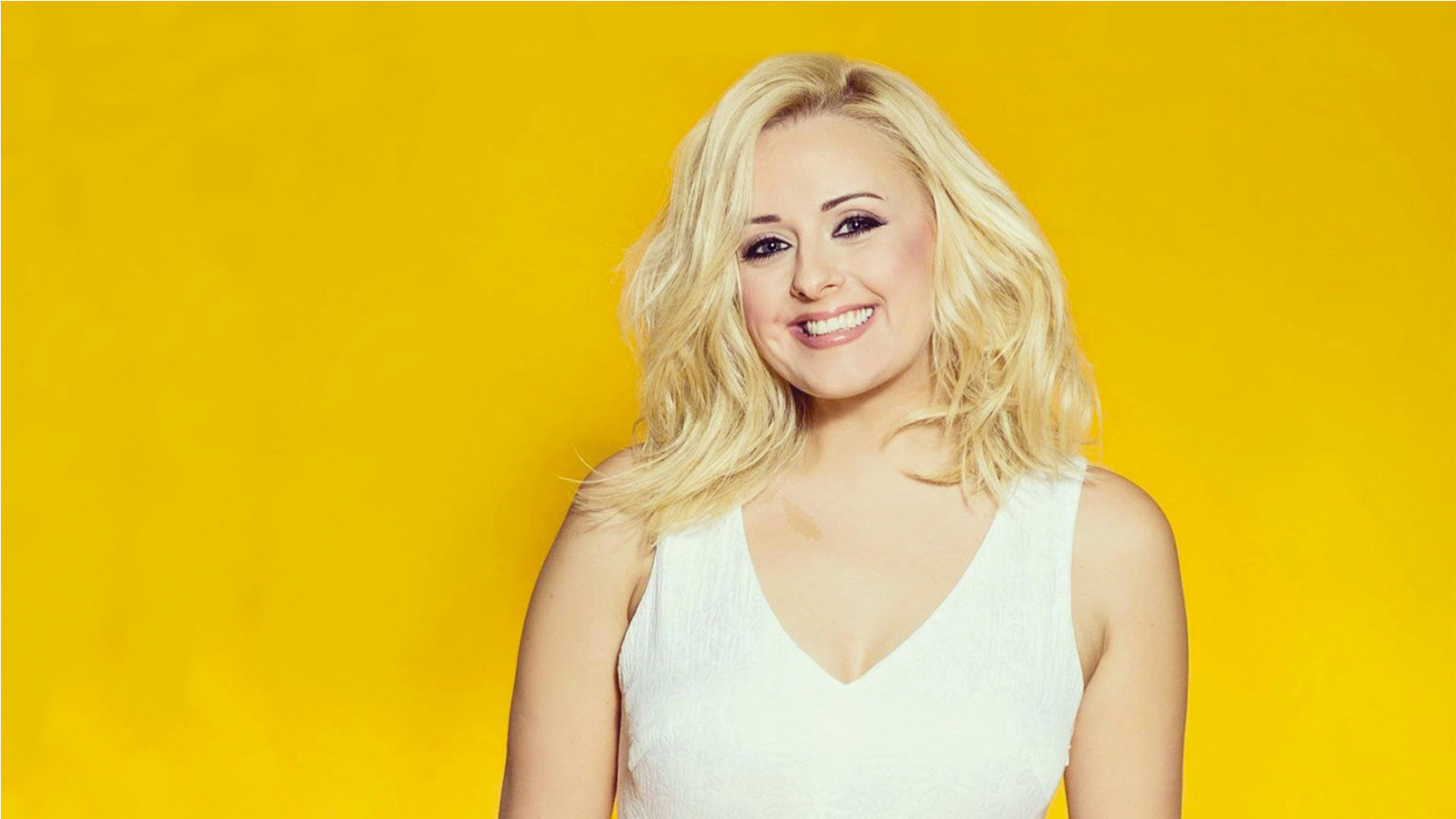 Katie Thistleton smiling and wearing a cream dress against a yellow background