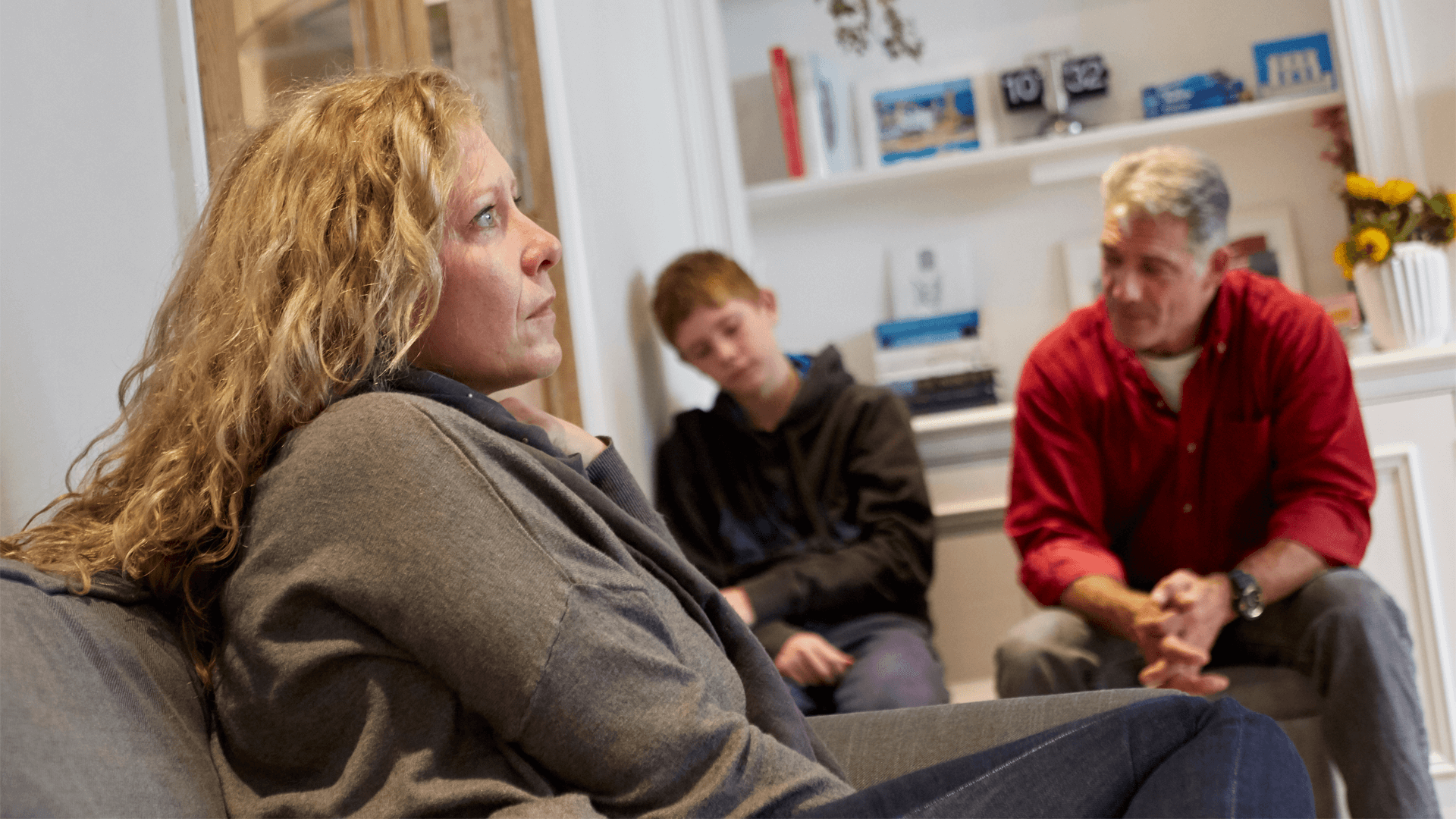 A family sitting in a room looking serious and sad