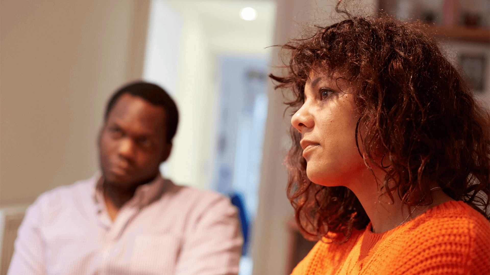 A man and woman sit in a room listening to something 