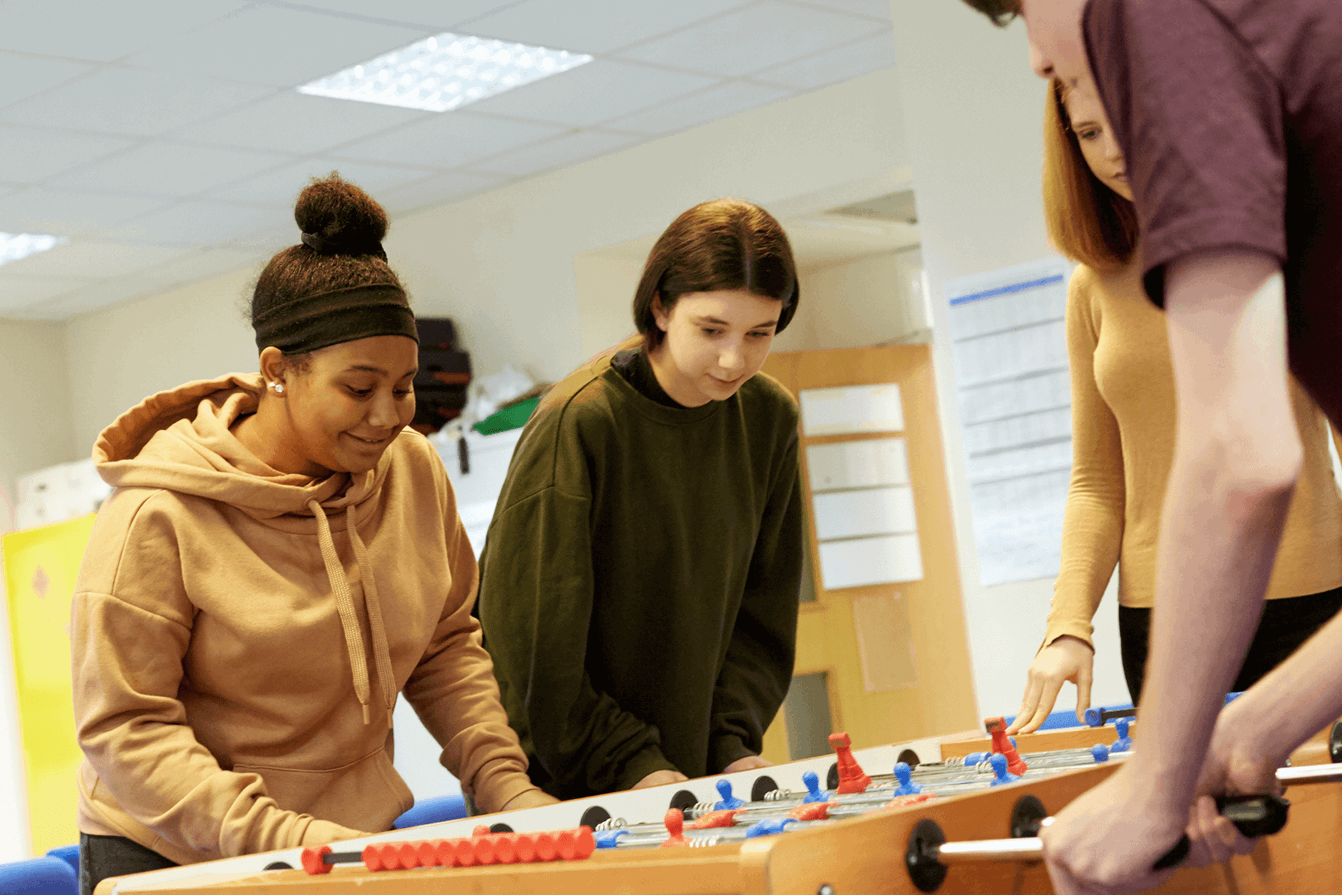four-young-people-serious-in-playing-table football in campus