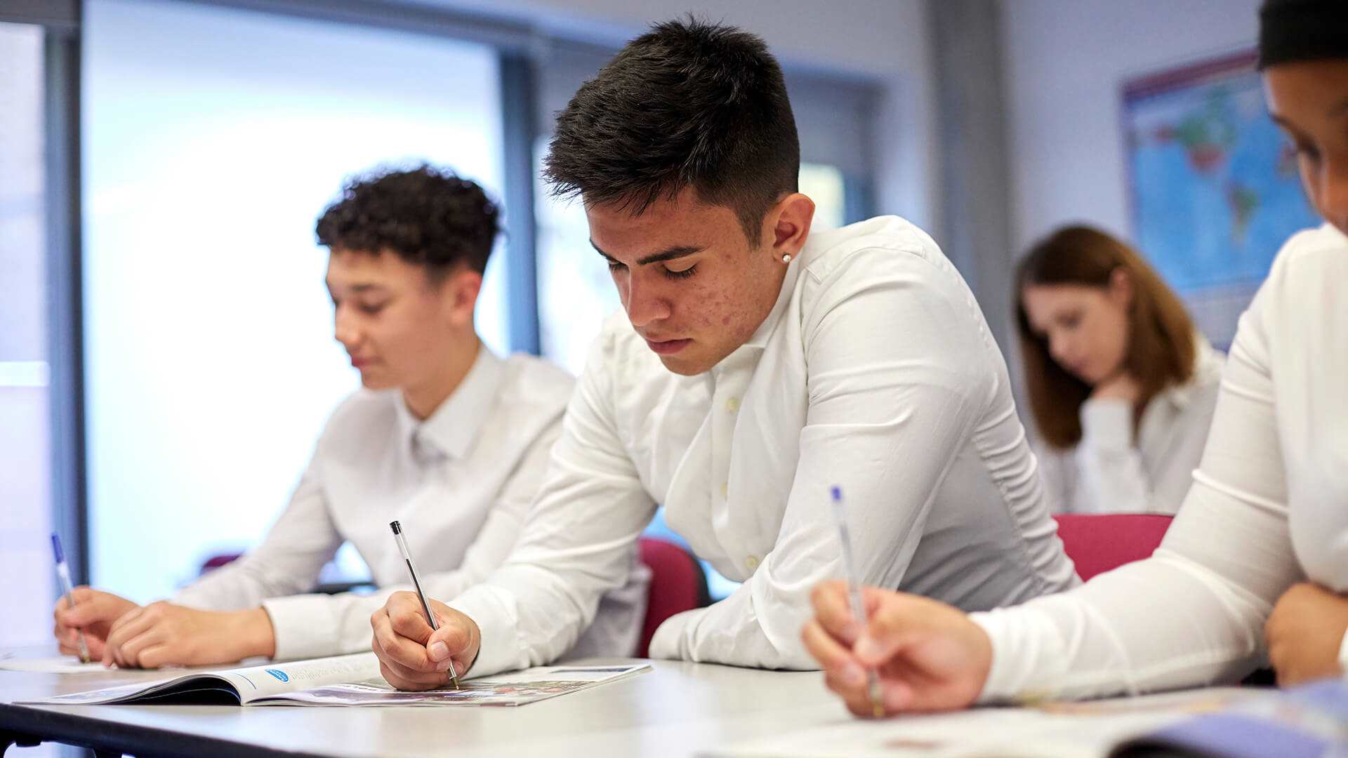 a-group-of-students-wearing-uniforms-writing-on-a-desk-while-classes-is-on-going