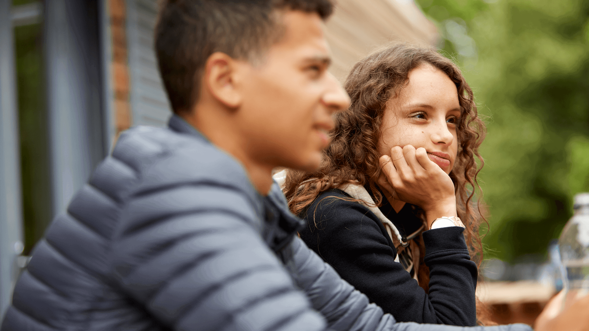 medium-shot-of-a-young-woman-with-a-curly-hair-and-hands-on-her-chin-thinking-while-another-young-man-is-beside-him-looking-away