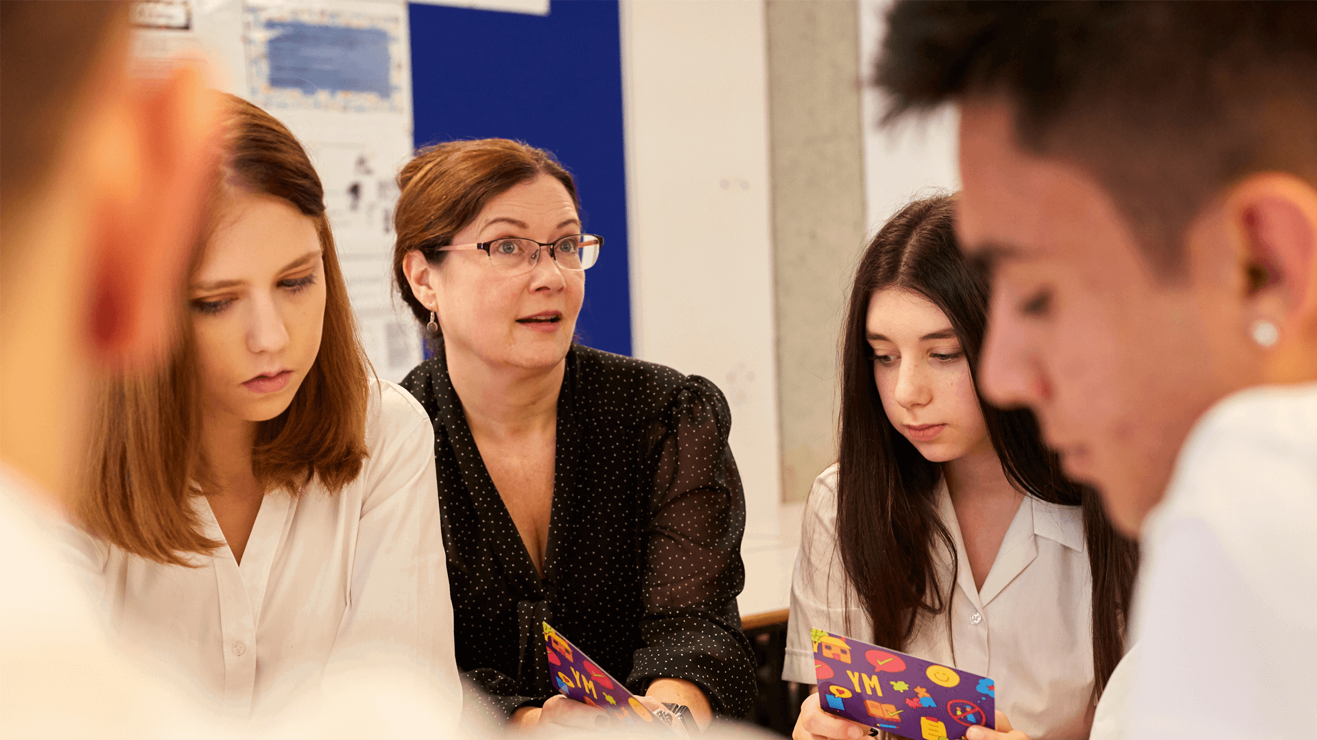 A close up of a female teacher sitting with her students