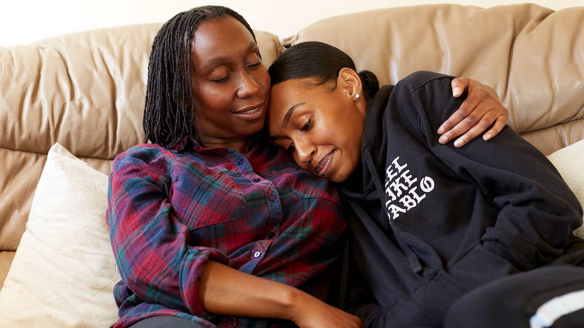 A mother hugging her daughter on the sofa