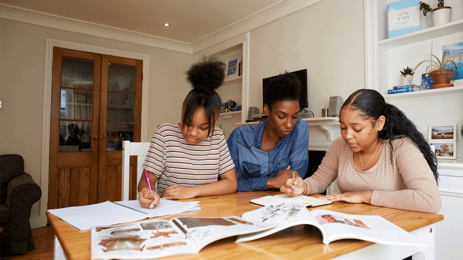 A mother and two daughters working together at a table doing homework