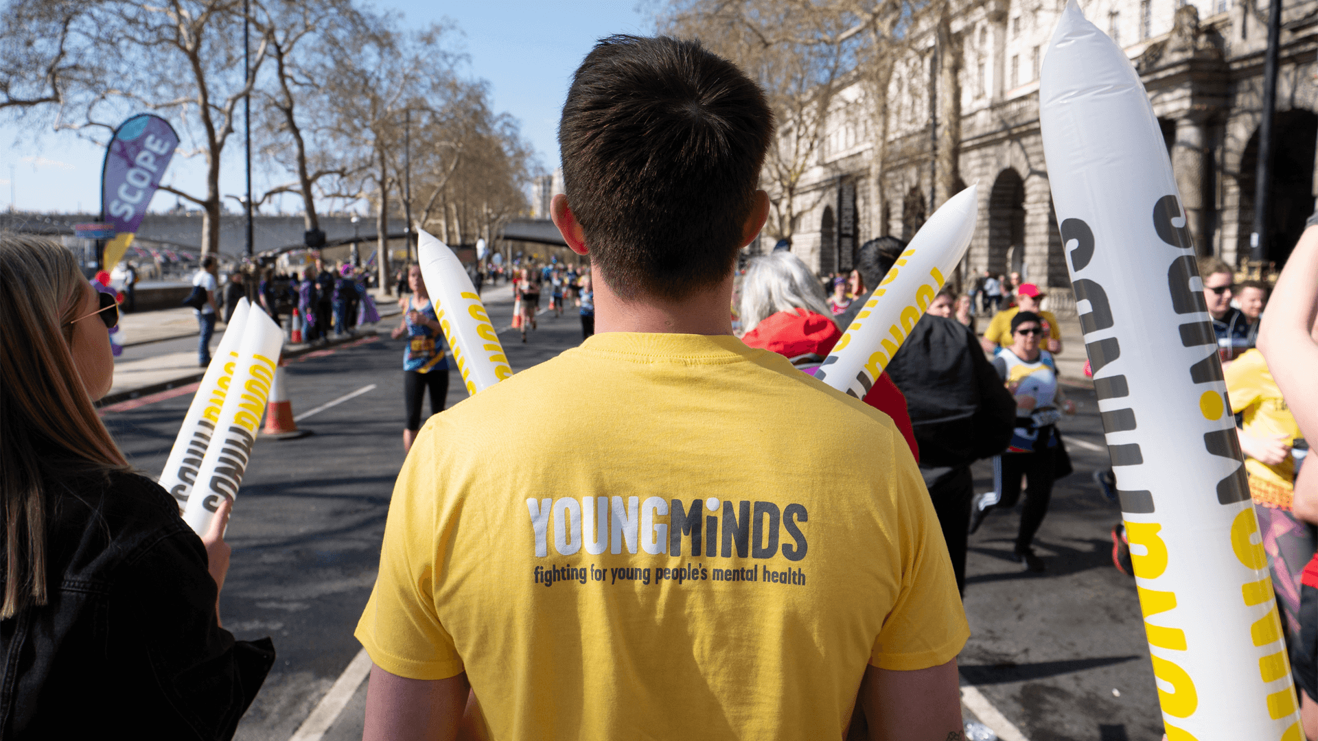 A YoungMinds volunteer wears a YM shirt and holding cheering sticks as he wait for the runners in the marathon