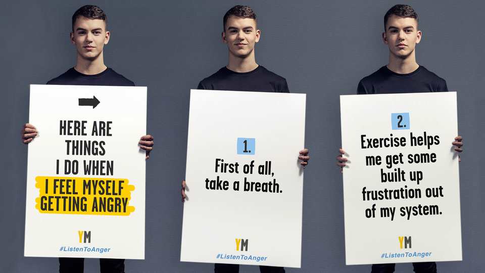 Three photos of the same person holding up placards. The person is wearing a black t-shirt. The first shot of them is that they are grinning and looking at the camera. In the middle shot, they are smiling while looking at the camera and the third they are looking serious at the camera.