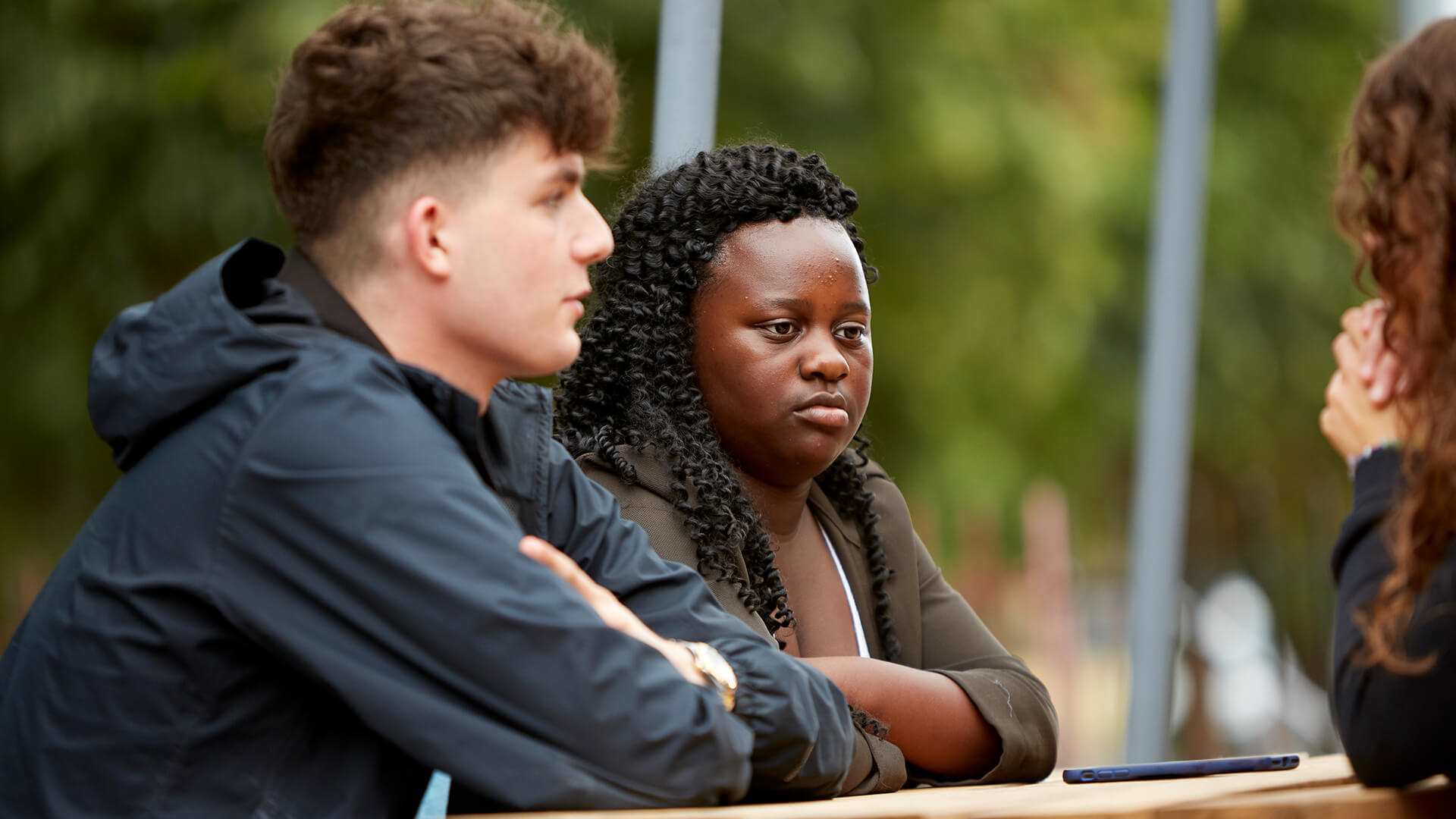 medium-shot-of-a-boy-and-a-girl-listening-seriously-to-a-while-sitting-on-a-dining-bench-in-the-park