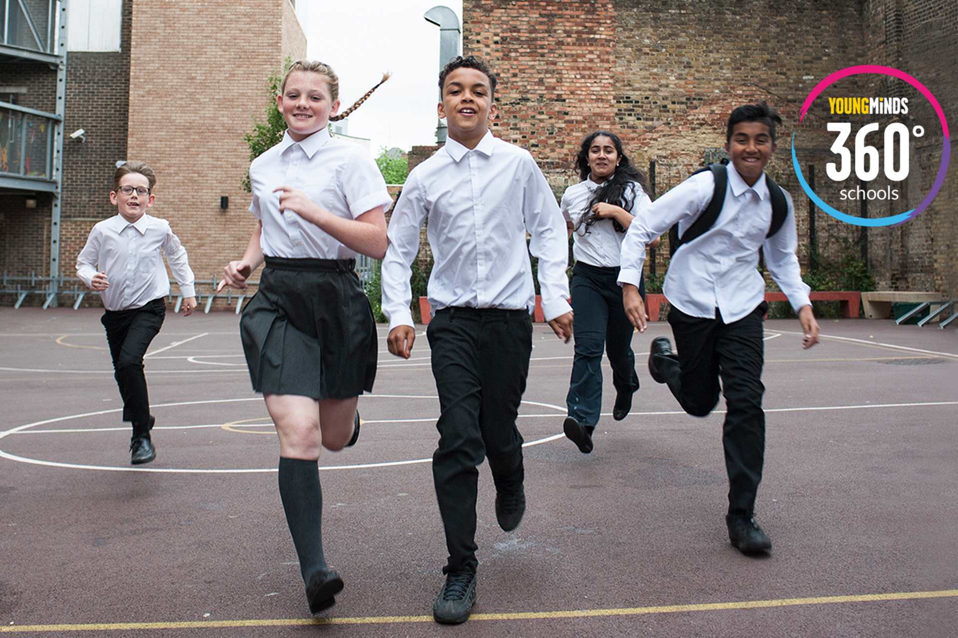 A group of pupils running in the playground with YoungMinds 360 logo