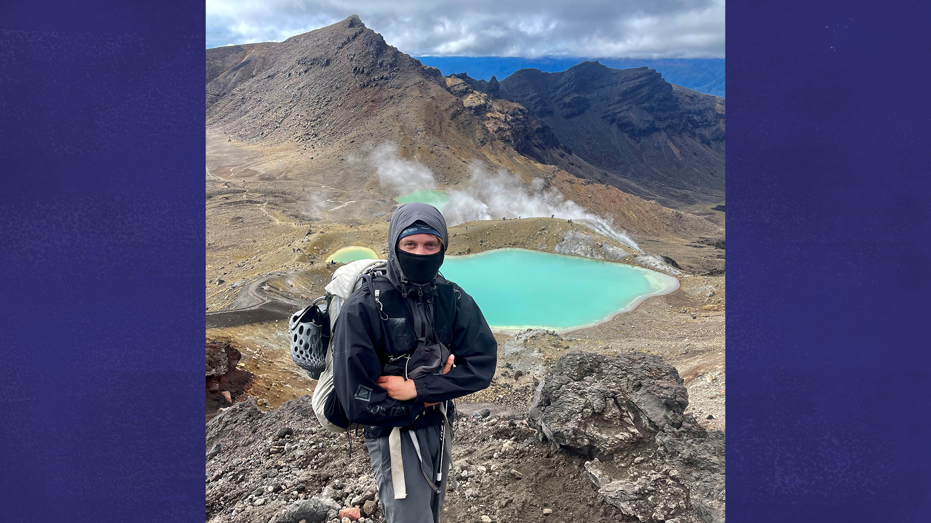 Charlie standing in front of a blue lake in the mountains.