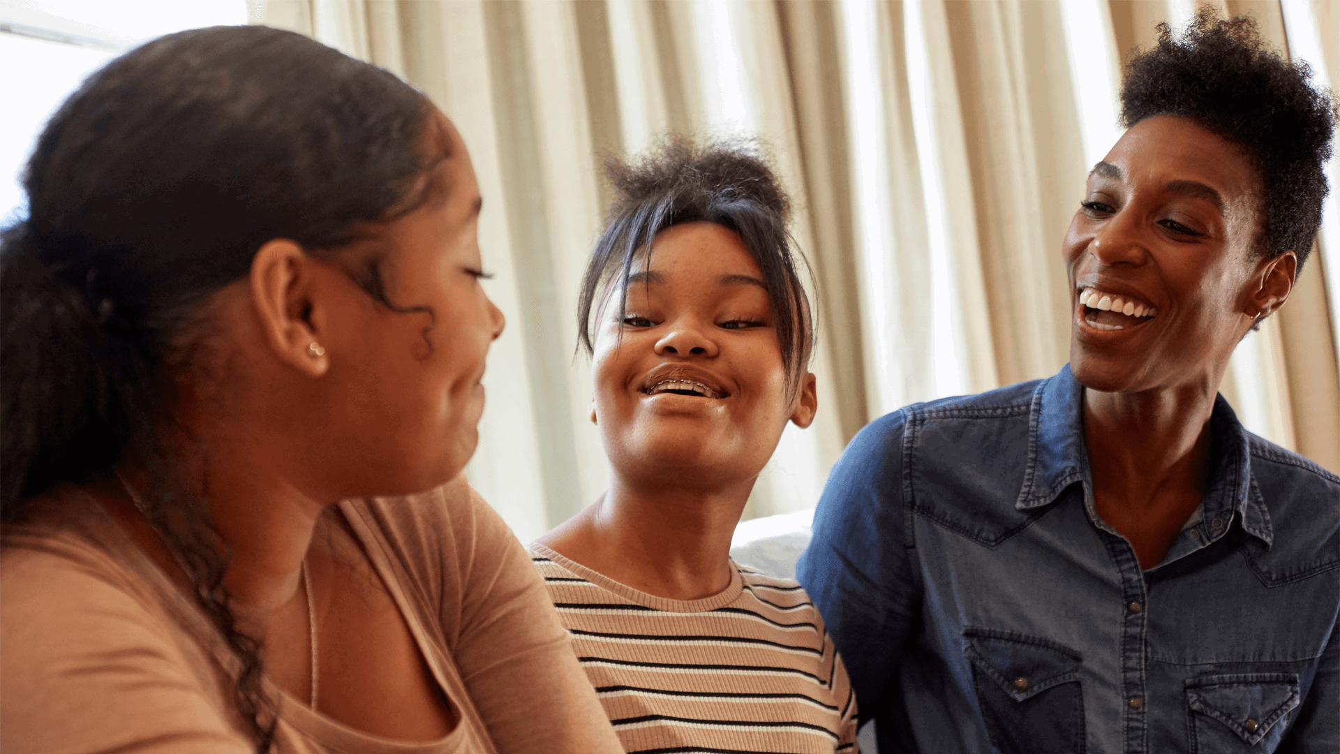 A mother and her two daughters smiling and laughing together