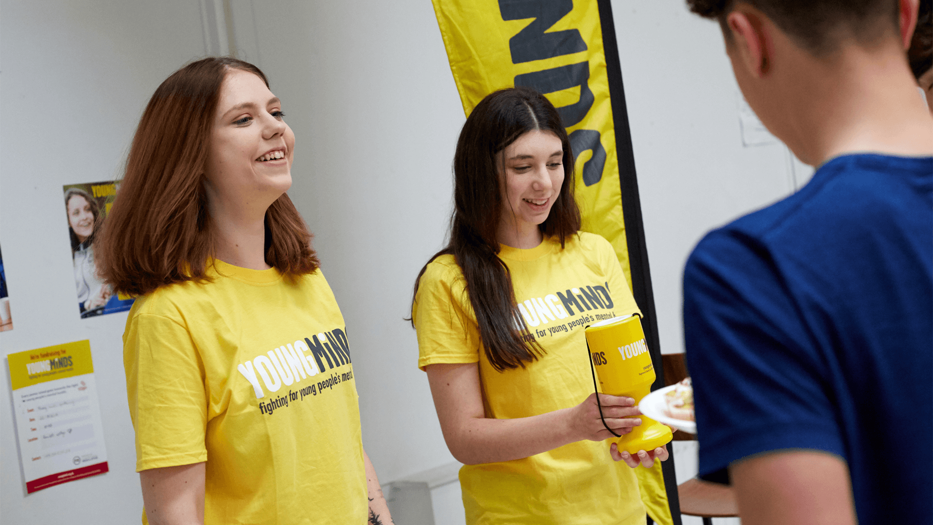 two fundraising volunteers wearing youngminds shirt smiling while giving out fundraising materials