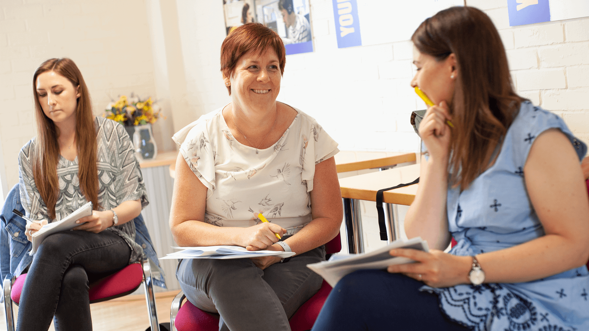 three mums are talking while working on an activity inside a classroom