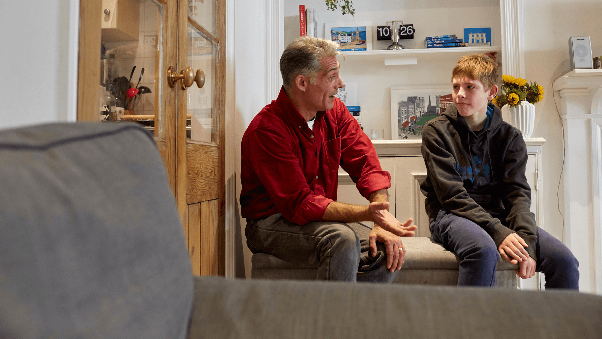 A father and son talking in a lounge seated 