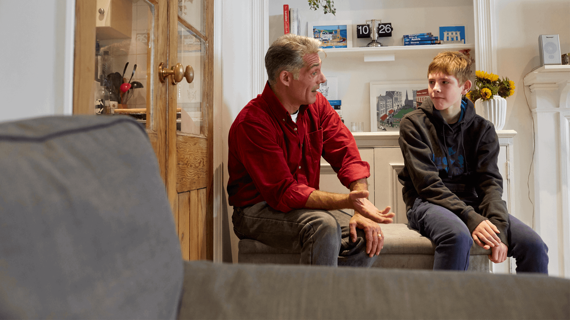 A father and son talking in a lounge seated 