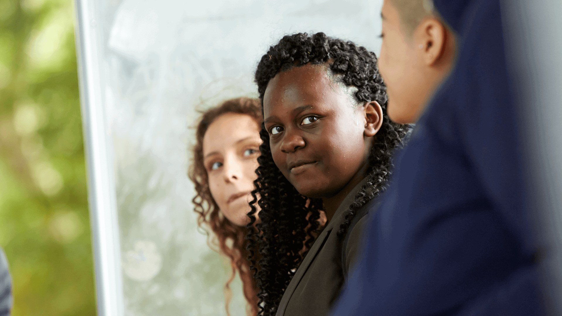 close-up-of-two-young-woman-with-curly-hair-looking-away-while-in-a-group-of-people