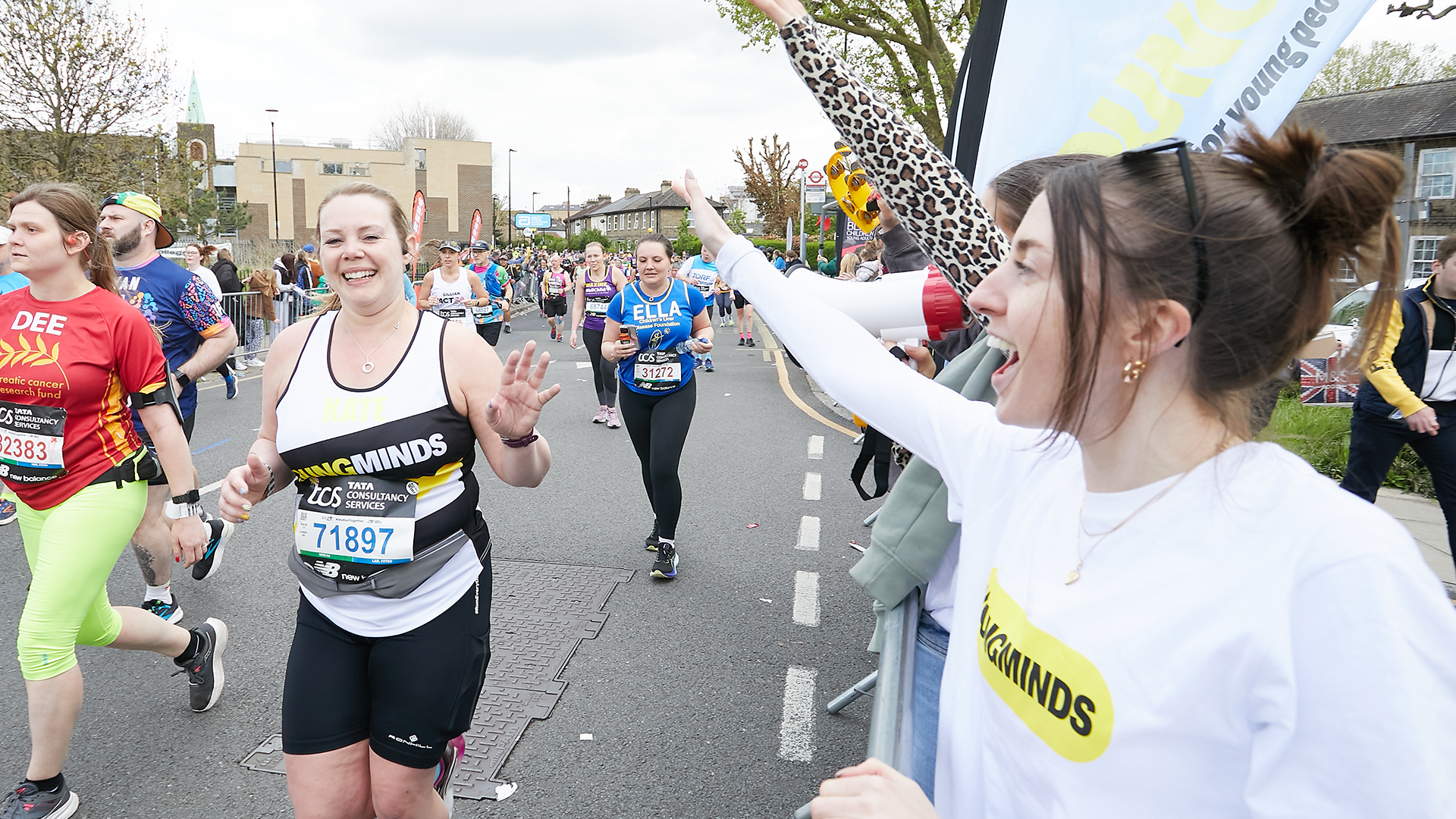A YoungMinds marathon runner being supported by YoungMinds staff on the side line.