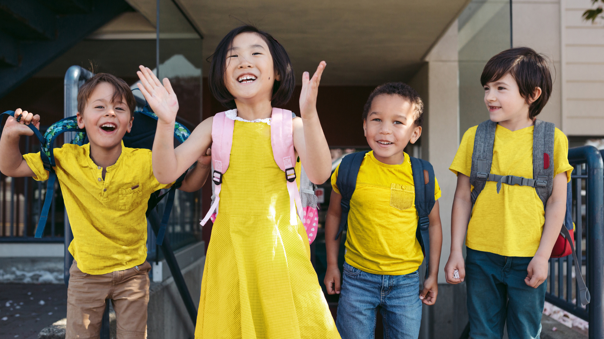 A group of school children, smiling and jumping and in bright yellow clothes.